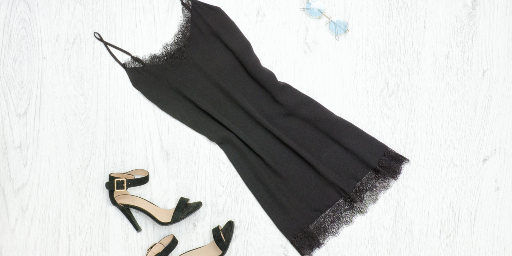 black dress and heels laid out on a bed