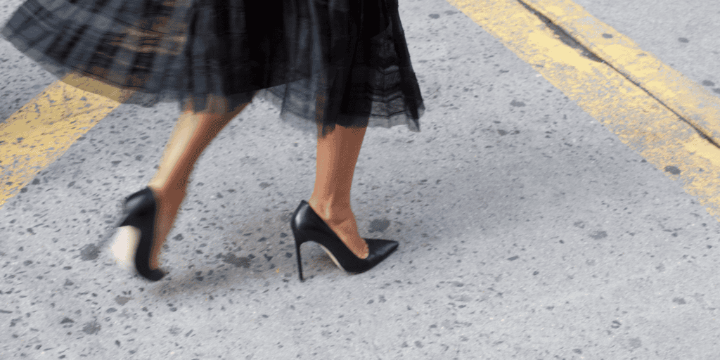 Woman running across the road in a black dress and black heels