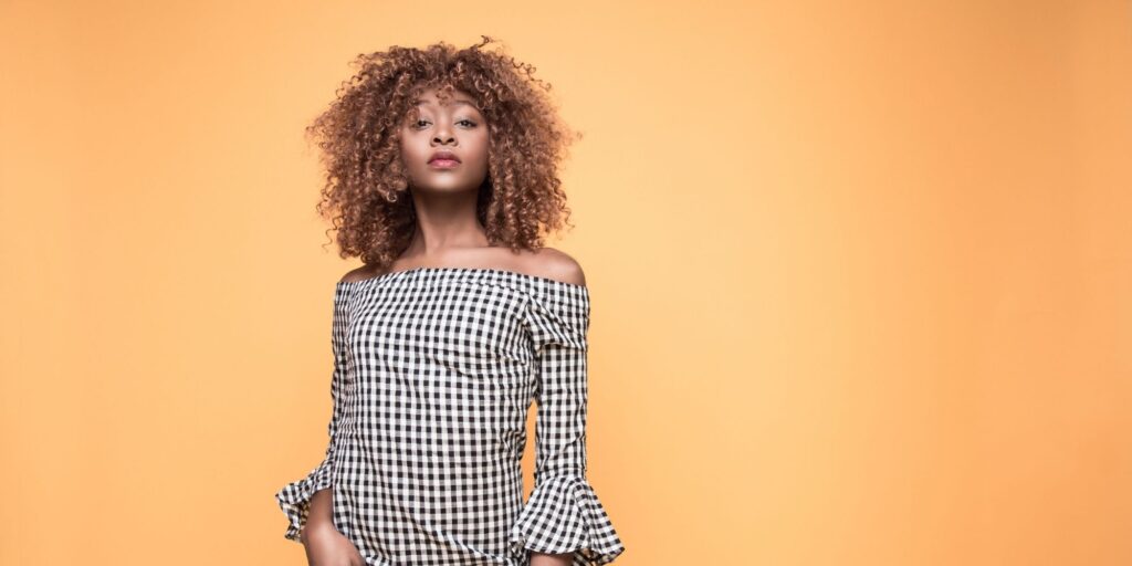 Confident woman with a checked dress against an orange wall