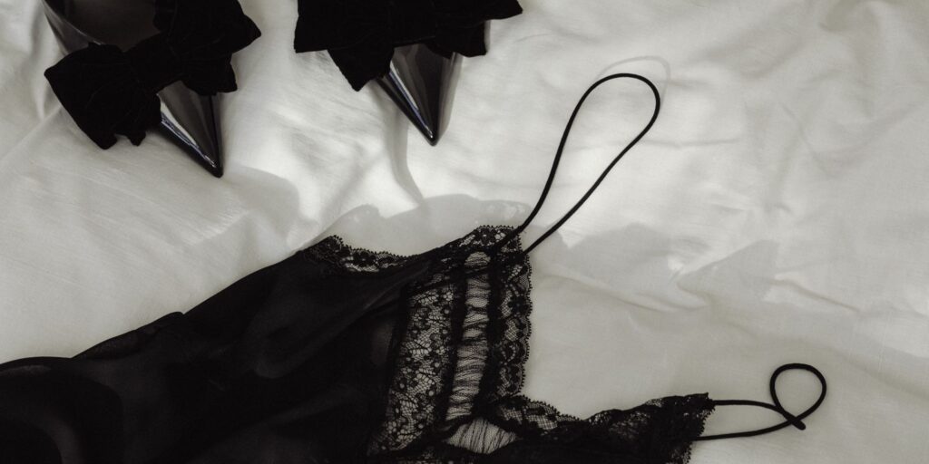 Black dress on a bed with black high heels
