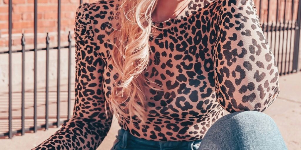 close-up of a woman with blonde hair, earing a cheetah print top