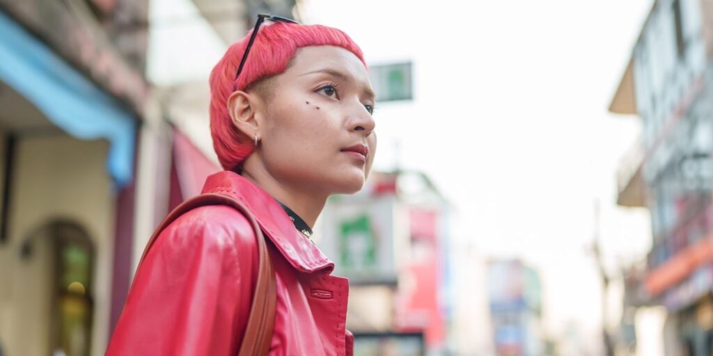 A woman with short pink hair and a matching pink jacket