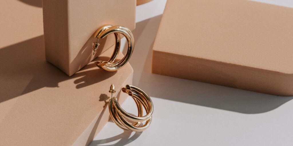 Van Cleef gold hoop earings being displayed on peach coloured boxes