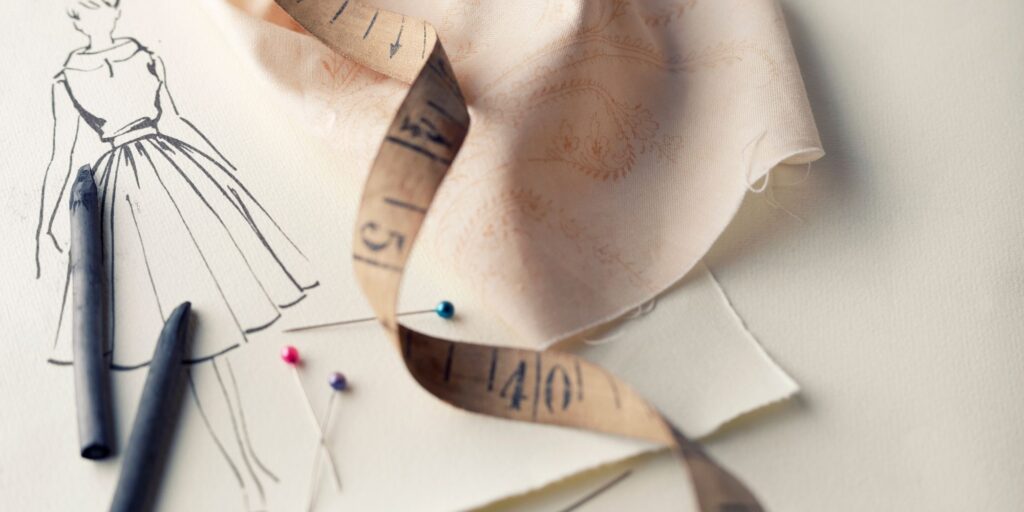 fashion design sketches of a dress and a measuring tape