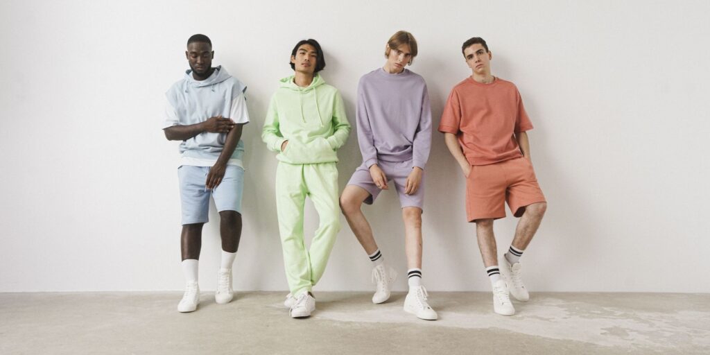 Four male models all wearing different pastel colours of sweatpants and hoodies
