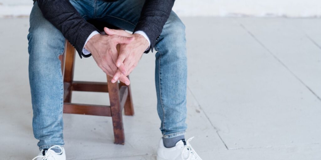 Man sat on a chair in jeans, sneakers and a blazer