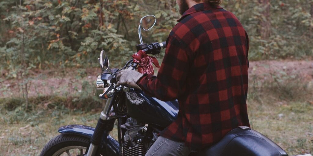 Man sitting on a motorbike with his back to the camera.