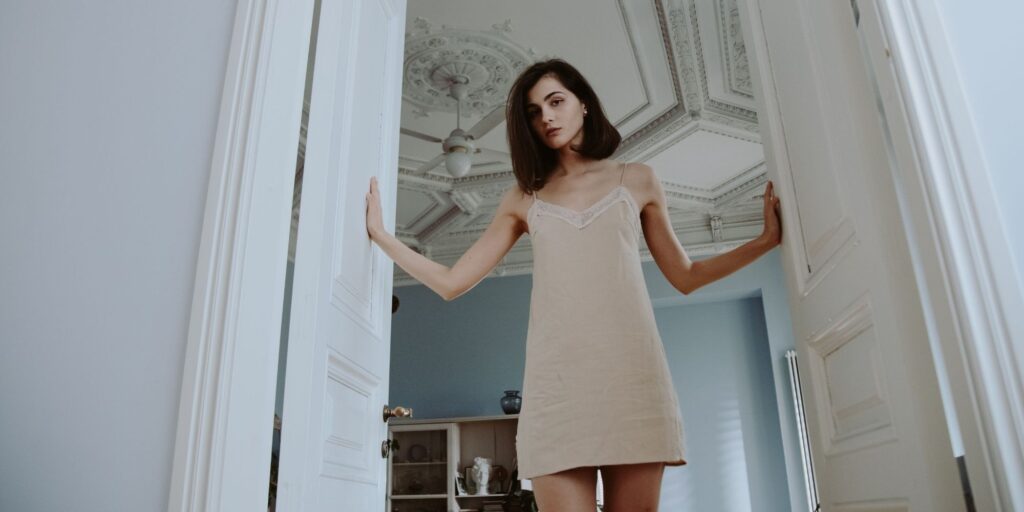 A woman wearing a simple slip sundress in an ornate room