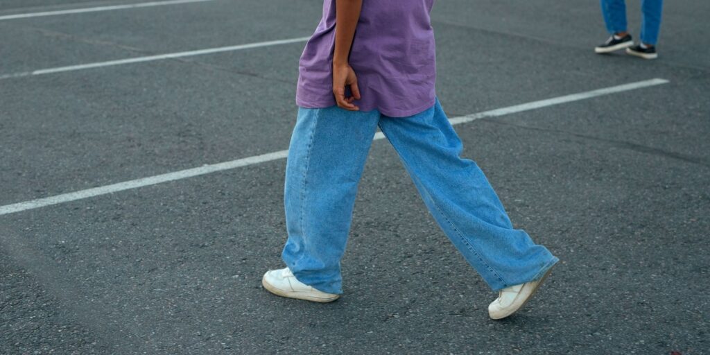 A teen walking with loose jeans and a purple t-shirt from ksubi
