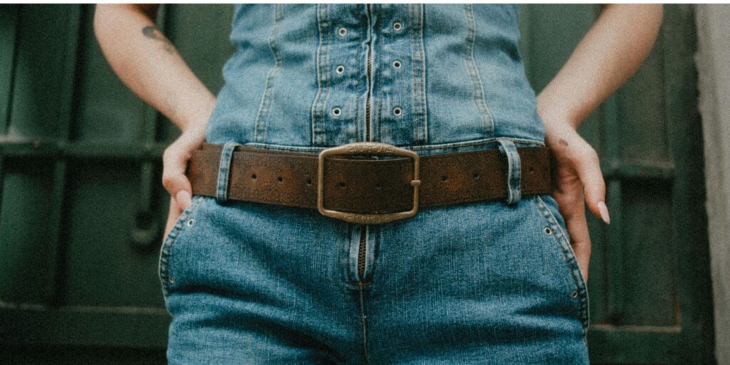 a brown belt holding up some denim jeans