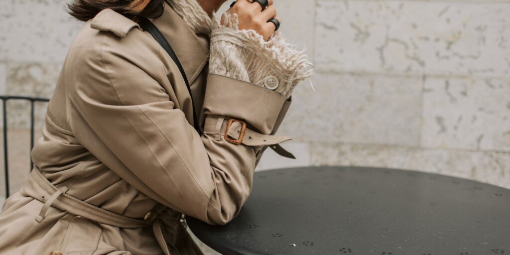 Woman sat at a table wearing a tan trench coat