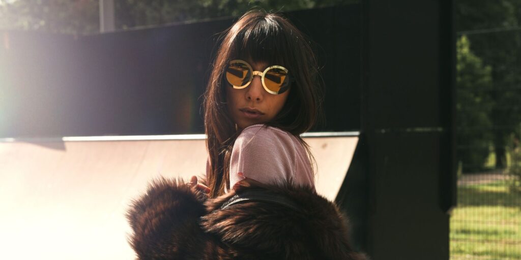 Woman with sunglasses wrapping her arms around her in a puffy coat