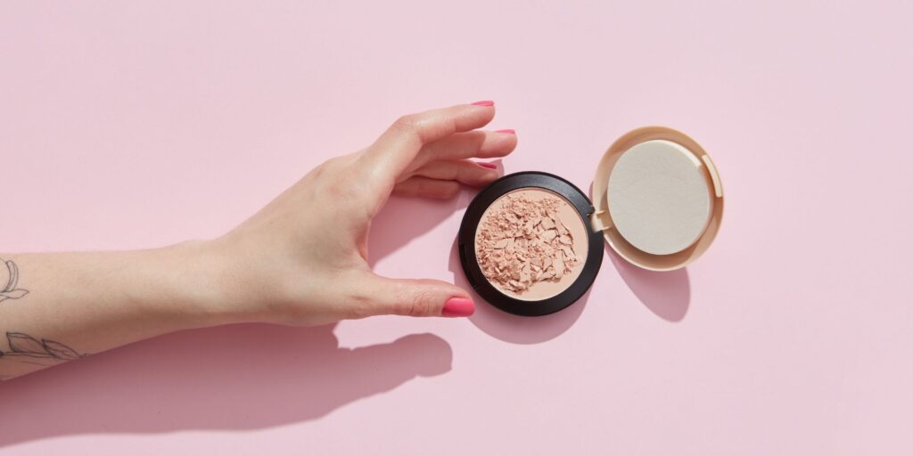 A hand reaching for a compact blush