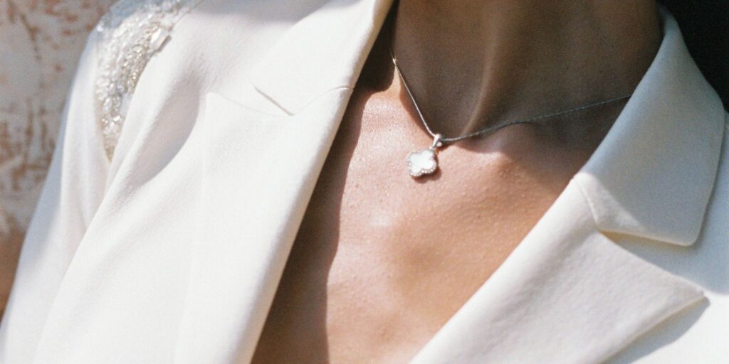 Close up of a van cleef necklace being worn by a woman in a white blazer