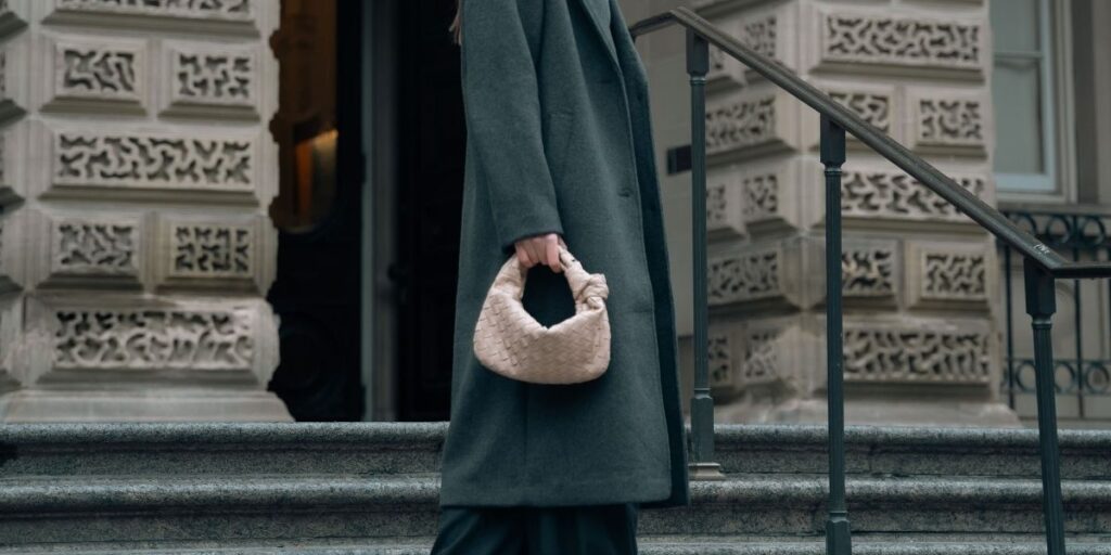 Cream bottega veneta bag held by a woman in a green coat